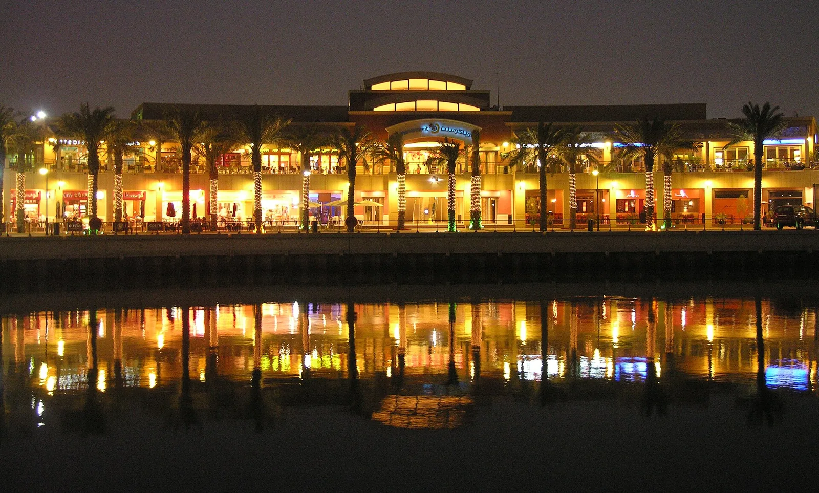 Marina Crescent buildings reflected in the water at night in Kuwait