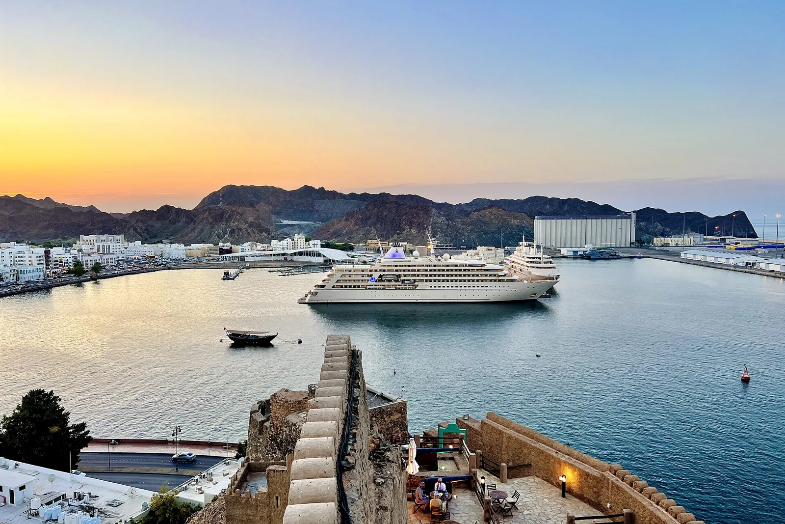 Muscat harbour and a cruise ship at sunset